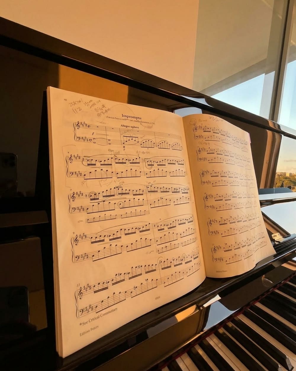 An open score on the music desk above the keys, pencil marks in the margins